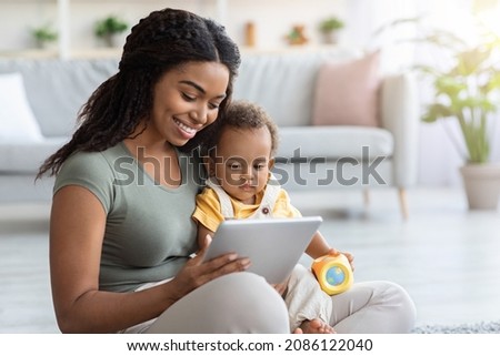 Smiling Black Woman And Her Adorable Infant Son Using With Digital Tablet At Home, Happy Family Of Two Relaxing With Modern Gadget, Watching Development Videos Or Cartoons Together, Free Space