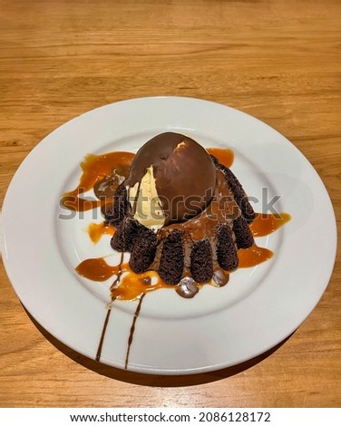 Molten chocolate lava cake with vanilla ice cream coated with chocolate on top.