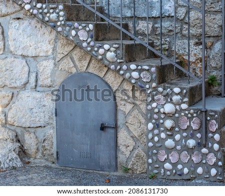 Old concrete stairs with railings decorated with seashells. Sea shells embedded in concrete.