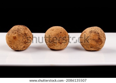 Beautiful candy truffle on a white plate on a black background close up