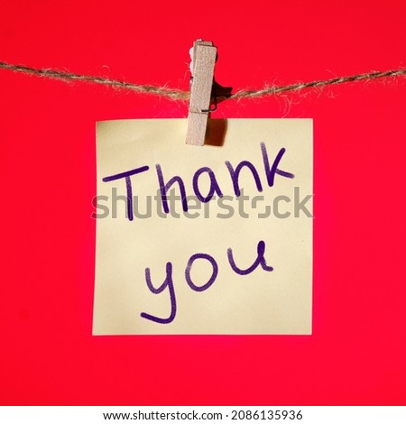 Writing Thank You on yellow paper on a red background.