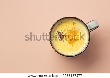 Curry latte or tea with curry and milk in a mug on a light pastel background top view. A healthy drink for immunity.