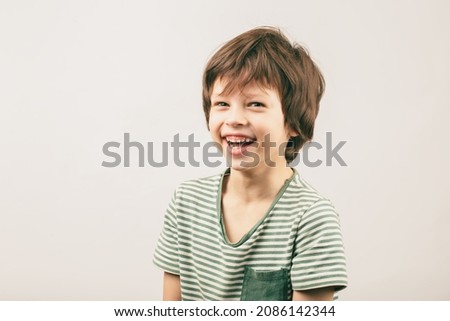 Happy six year old Caucasian boy portrait over grey background. White European kid widely smiling and looking into the camera Royalty-Free Stock Photo #2086142344