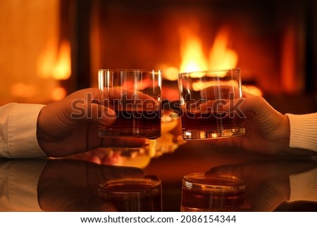 Young couple has romantic dinner with whiskey over fireplace background. Romantic concept. Royalty-Free Stock Photo #2086154344