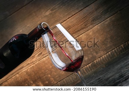 Pouring red wine into the glass on wooden background