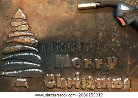 A steel sheet of metal on which a Christmas tree is welded and the phrase Merry Christmas. Christmas card for workers in heavy industry and metalworking. 