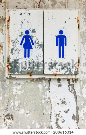 Public toilet sign on weathered wall