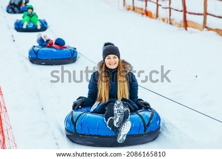 smiling woman on snow tube pulled up by winter hill