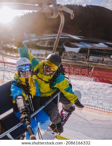 couple taking selfie while going up on chairlift ski resort