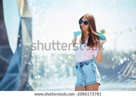 young skateboarder girl with skateboard standing outdoors