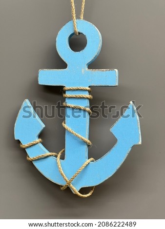 Wooden worn blue anchor on a gray background