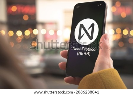 Near Protocol cryptocurrency symbol, logo. Business and financial concept. Hand with smartphone, screen with crypto icon close-up Royalty-Free Stock Photo #2086238041
