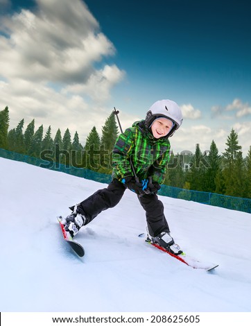 Little skier going down from snowy hill