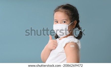 Coronavirus Vaccination Advertisement. Happy Vaccinated Little asian girl Showing Arm With Plaster Bandage After Covid-19 Vaccine Injection Posing Over Blue Background, Smiling To Camera. New normal. Royalty-Free Stock Photo #2086269472