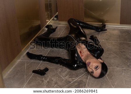 Hit woman. Woman in a latex suit killed in gunfire shot in the chest

 Royalty-Free Stock Photo #2086269841