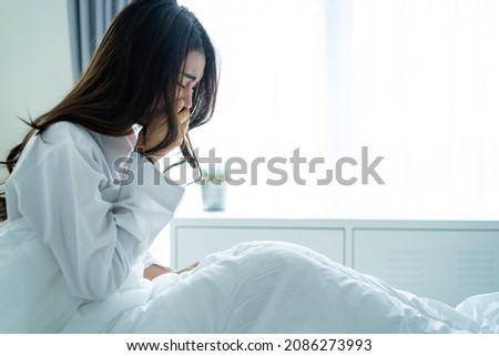 Asian beautiful sick girl in pajamas getting up from sleep in bedroom. Attractive young woman feeling bad after wake up on bed and coughing in early morning at home. health care-lifestyles concept. Royalty-Free Stock Photo #2086273993