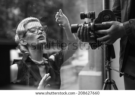 Elegant blond retro woman in black dress with camera 
