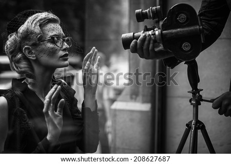 Elegant blond retro woman in black dress with camera 
