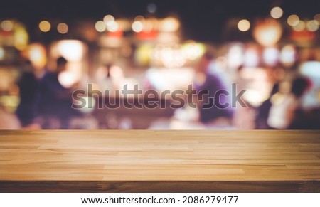 Selective focus.Wood table top with blur light bokeh in dark night cafe,restaurant background.Lifestyle and celebration concepts