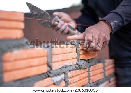 A hand of construction worker, industrial bricklayer installing bricks on construction site. Royalty-Free Stock Photo #2086310935
