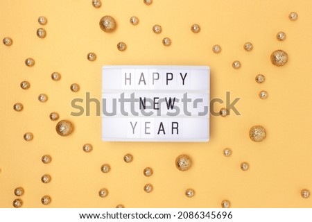 Happy New Year. Lightbox and round glittering confetti on a golden background.