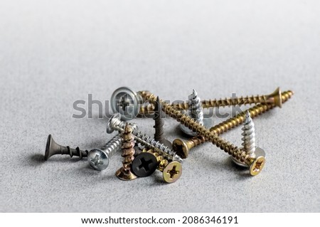 Fasteners - self-tapping screws, screws of different sizes on grey background. Furniture fittings. Connecting pieces. Copy space.