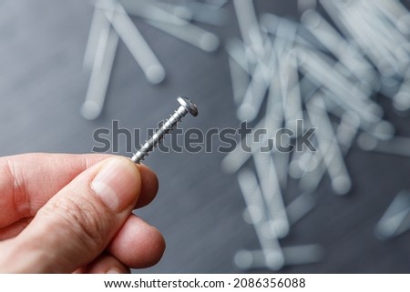 Hand holding one steel screw on a black and white background