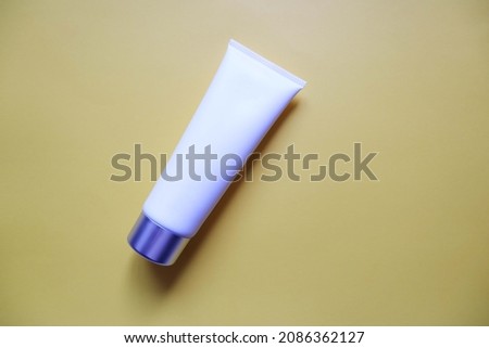 White squeeze bottle plastic tube on yellow background. spa and cosmetics concept, flat lay, top view. Mockup, template.
