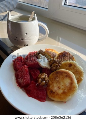 Homemade delicious morning breakfast with a cup of tea, cottage cheese pancakes, strawberry jam and nuts