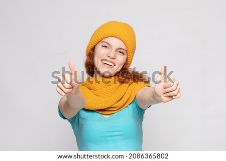 a young girl in a warm yellow hat and scarf on a light background