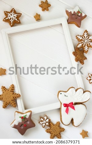 Gingerbread reindeer Christmas Cookie , stars, snowflakes on white wooden board, wooden phote frame with empty space.Christmas border, Christmas template for sale, greeting cards, advertising