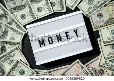 Lightbox board with the word MONEY in black letters around Us dollars banknotes. Finance background. Business, financial success and making money concept. Business budget of wealth and prosperity 