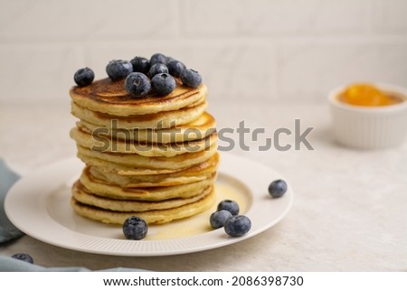Pancakes with honey, jam and decorated with blueberries in a plate on the table
