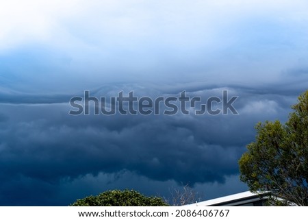  Storm clouds above trees and roofs. Heavy torrential rain. Rainfall flash flooding. Meteorology weather forecast. Low-pressure area. La Nina climate