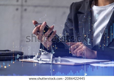 A woman financial trader in formal wear is checking the phone to sign the contract to invest money in stock market. Internet trading and wealth management concept. Forex hologram chart.