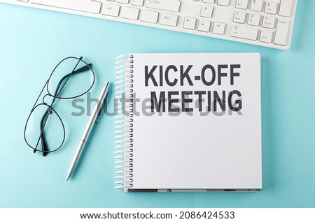 Keyboard, notebook,pen and glasses on blue background , text KICK OFF MEETING Royalty-Free Stock Photo #2086424533