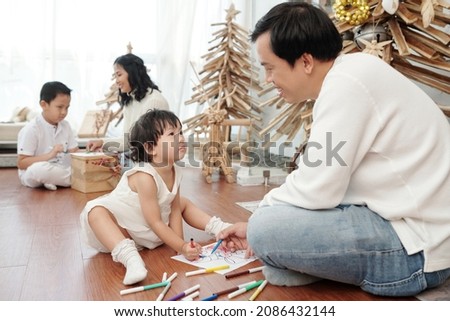 Happy father and daughter drawing Christmas pictures on the floor