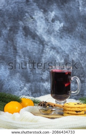 Mulled wine in a cup with cranberries and spices on the background of a white sweater
