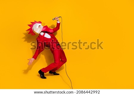 Photo of funky carefree incognito guy hold mic sing song wear rooster mask red tux isolated yellow color background