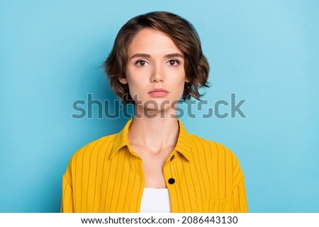 Photo of charming pretty calm lady bob hairdo look camera wear yellow striped shirt isolated blue color background