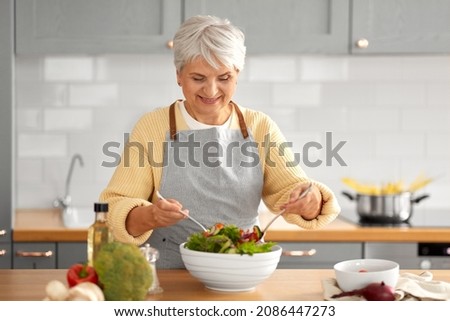 healthy eating, food cooking and culinary concept - happy smiling senior woman making vegetable salad on kitchen at home Royalty-Free Stock Photo #2086447273