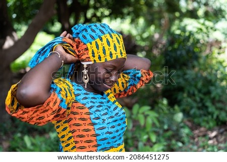 Beautiful black African woman fixing her colored scarf on her head Royalty-Free Stock Photo #2086451275