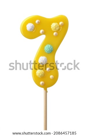 Front view of yellow handmade number seven lollipop isolated on white