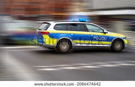 German police emergency vehicle with blue lights on speeds through an intersection, intentional motion blur of background