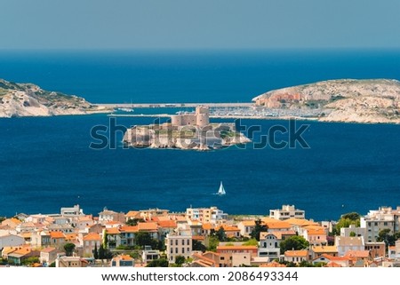 View of Marseille town and Chateau d'If castle famous historical fortress and prison on island in Marseille bay with yacht in sea. Marseille, France Royalty-Free Stock Photo #2086493344