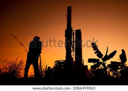 Working drill the artesian on sunset silhouette sky background, 
farmland in countryside or rural for drill the artesian on dirt ground, beautiful view landscape for working about soil technology Royalty-Free Stock Photo #2086499863