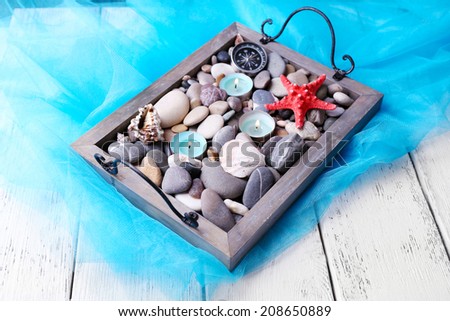 Candles on vintage tray with sea pebbles,starfish and sea shells on wooden background