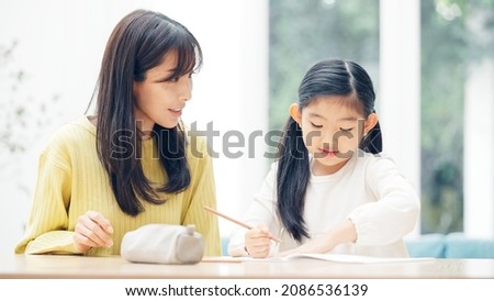 Asian little girl and mother studying at home. Education concept. Royalty-Free Stock Photo #2086536139