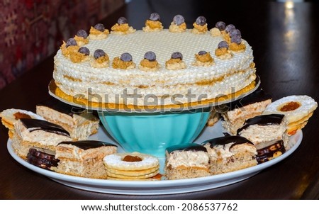 Sweet creamy wafer gateau and small cakes on a plate Royalty-Free Stock Photo #2086537762
