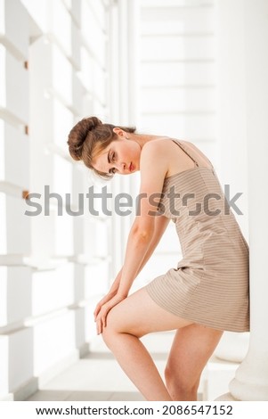 Portrait of a young beautiful girl in a short beige dress